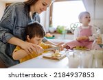 Mother of two little children preparing breakfast in kitchen at home.