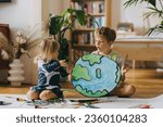 Small photo of Siblings painting at home with watercolors and tempera paints, creating a model of planet Earth.