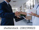 Small photo of Pharmaceutical sales representative shaking hand with female doctor in medical building. Hospital director consulting with healthcare staff.