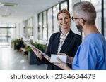 Small photo of Pharmaceutical sales representative talking with doctor in medical building. Ambitious female hospital director consulting with healtcare staff. Woman business leader.