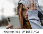 Small photo of Portrait of teenage girl looking at her smartphone, sad, anxious, alone. Cyberbullying, girl is harassed, threated online.