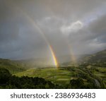 View of the beautiful Hanalei Valley with a double rainbow and rain clouds from the Hanalei Valley Lookout in Princeville, Kauai, Hawaii, United States. 
