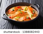 Asian cuisine. Salmon with coconut sauce, lime and herbs close-up in a frying pan on the table. horizontal