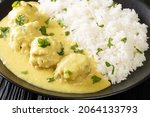 Small photo of Popular Danish family dish boller i karry or meatballs in curry sauce with rice close up in the plate on the table. horizontal