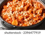 Small photo of Classic Swedish Dish Flygande Jakob made of chicken, cream, chilli sauce, bananas, roasted peanuts and bacon closeup on the pan on the table. Horizontal