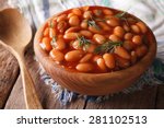 white beans in tomato sauce in a wooden bowl closeup. horizontal