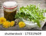 Foraged edible dandelions flowers and greens with jar of dandelion preserve