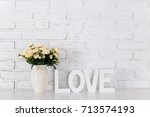 wooden letters forming word LOVE and flowers over white brick wall background
