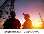 two worker watching the power tower and substation with sunset background