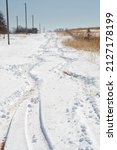 Small photo of Wavering tire tracks left by a vehicle struggling to go uphill in deep unplowed snow after a snow storm