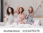 Luxury bachelorette party in posh apartment while happy young three women 20s having fun and drinking champagne under falling confetti