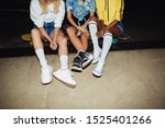 Cropped image of young multinational girls in streetwear sitting on skateboards at night party outdoors