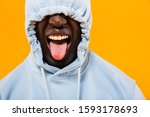 Image of funny african american guy in streetwear hoodie sticking out his tongue isolated over yellow background