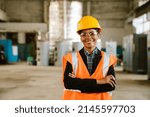 Black woman wearing helmet and vest smiling while working at factory