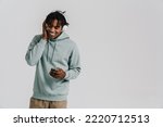 Young african man listening music with headphones using mobile phone isolated over white background