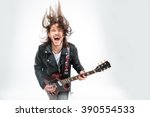 Excited young man in black leather jacket with electric guitar shouting and shaking head over white background