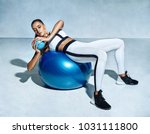 Beautiful girl doing fitness exercise abs on gymnastic ball. Photo of sporty girl in sportswear on grey background. Fitness and healthy lifestyle concept