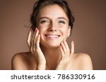 Attractive young girl touching her face on beige background. Beauty & Skin care concept