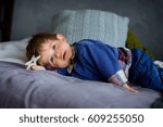 Small photo of The little boy was tired of a game. The kid has lain down on a pillow. He is sleepy. In a hand a toy.