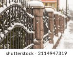 Steel fence combined with stones. Covered by snow.