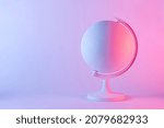 Model of a globe with blank map in pink and purple gradient light. Geography concept with copy space