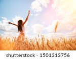 Happy woman enjoying the life in the sunny field. Nature beauty, blue sky,white clouds and field with golden wheat. Outdoor lifestyle. Freedom concept. Woman jump in summer field