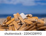 Small photo of Cigarette stubs dropped and left in a pile on a beautiful beach