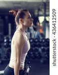 Small photo of Young slim woman doing pushdown on cable machine in gym. Athletic girl training triceps in fitness center. Toned image