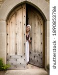 Small photo of Woman in medieval wench outfit standing in the door of a French medieval castle