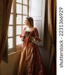 Small photo of Woman wearing authentic Renaissance costome and headdress standing at her window in a medieval castle