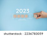 Female hand putting wooden cube for countdown to 2023. Loading year from 2022 to 2023. New year start concept