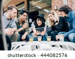 Group of young multiethnic friends sitting in a bar having a drink, talking to each other holding a smart phone, having fun - happy hour, friendship, relax concept