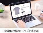 People buying casual shirt on ecommerce website with smart phone on wooden desk