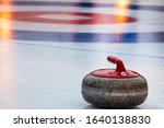 Curling red stone on playing field on an ice rink during competition