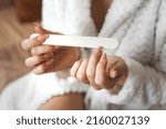 Small photo of Closeup photo of young womans hand makes herself a manicure, files her nails with a nail file. Personal hygiene