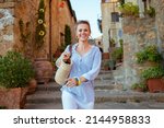 Small photo of Travel in Italy. happy trendy woman with straw bag having excursion in Pienza in Tuscany, Italy.