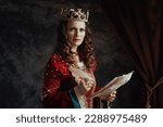 Small photo of medieval queen in red dress with parchment and crown on dark gray background.
