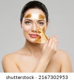 Small photo of Beauty Woman peeling off Golden Facial Mask. Smooth Skin Model taking off Gold Purifying Face Film Mask over Gray. Women cleansing Cosmetics and Skincare Cosmetology