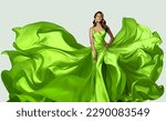Small photo of Fashion Model in Green Dress with flying Silk Fabric. Beautiful Girl in Satin Evening Gown over White. Happy Woman in Spring Skirt fluttering on Wind