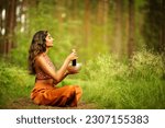 Small photo of Indian Woman playing Tibetan Singing Bowls with Mallet Outdoors. Relaxing Meditative Music Therapy and Sound Healing. Spiritual Yoga Meditation Practice in Forest