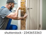 Professional locksmith reparing door lock with screwdriver. Industrial theme