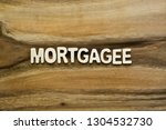 Small photo of Plywood alphabets on acacia wooden texture background concept. The word "MORTGAGEE" on wood pattern backdrop.