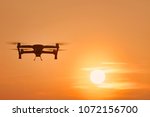 Drone quad copters with high resolution digital camera flying aerial over spectacular sunset orange sky