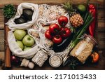 Zero waste food shopping. Fruit and vegetables in cotton bags, pasta, cereals and legumes in glass jars, herbs and spices on wooden background. Healthy food, clean eating, eco friendly, no plastic con