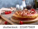 Homemade Italian bread (focaccia) with cherry tomatoes, rosemary and olive oil on a wooden serving board, selective focus. Italian home cooking concept.
