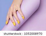 Nails Design. Hands With Bright Yellow Manicure On Violet Background. Close Up Of Female Hands With Trendy Orange Nails On Purple Background. Art Nail. High Quality Image.