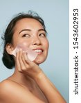 Small photo of Face skin care. Smiling woman using facial oil blotting paper portrait. Closeup of beautiful happy asian girl model with natural makeup using oil absorbing sheets, beauty product at studio
