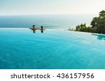 Romantic Vacation For Couple In Love. Happy People Relaxing In Infinity Edge Swimming Pool Water, Enjoying Beautiful Sea View. Man, Woman Together On Summer Travel To Luxury Resort. Summertime Relax