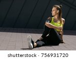 Woman Listening Music, Doing Workout Exercises On Street. Beautiful Athletic Fit Girl In Bright Sports Clothing Stretching Her Legs And Relaxing After Fitness Training On Street. High Quality Image