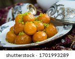 Small photo of Traditional oriental dessert speciality called luqaimat, fried dough balls in a plate being drizzled with dibs (date syrup). Luqaimat is a popular Arabian dessert that is often eaten during Ramadan.